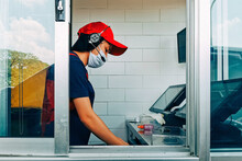 Bangkok, Thailand - May 28, 2020 : Fast Food Cashier In Drive Thru Service Wearing Hygiene Face Mask To Protect Coronavirus Pandemic Or Covid-19 Virus Outbreak Working On Counter At The Station.