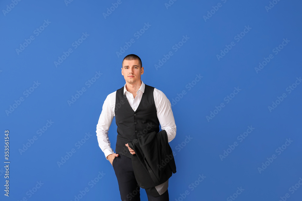 Handsome young man in elegant suit on color background