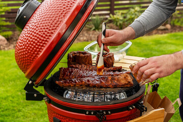 Red Ceramic Barbecue Grill.  Grilling, Smoking, Baking, BBQ and Roasting process. Post-quarantine Picnic in modern homes terrace. Lifestyle concept.