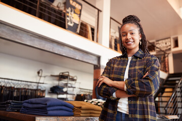 Wall Mural - Portrait Of Smiling Female Owner Of Fashion Store Standing In Front Of Clothing Display