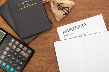 Wall Mural - top view of bankruptcy paper, law book, money bag and calculator on wooden background