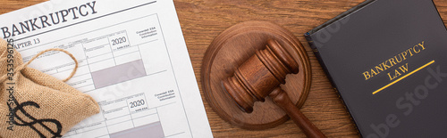 Fotomural top view of money bag, bankruptcy paper, law book and gavel on wooden background