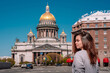 Portrait of a girl with long hair in a sweater on a Sunny summer day against the background of St. Petersburg street, with St. Isaac's Cathedral