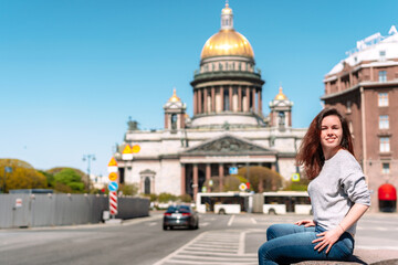 Portrait of a girl with long hair in a sweater on a Sunny summer day against the background of St. Petersburg street, with St. Isaac's Cathedral