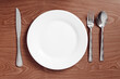 © Gregory - serving metal cutlery lie on a wooden table next to a plate