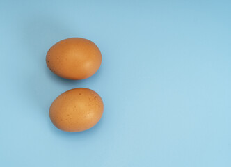 Two brown raw eggs on a blue background, top view