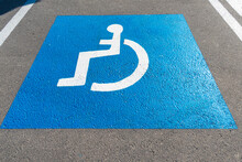 Parking Lot With Painted Handicapped Symbol Of Wheelchair On Asphalt, Parking Spaces For Disabled Visitors. Empty Disabled Parking Space