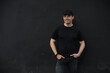 Stylish man in t-shirt standing leaning on black wall