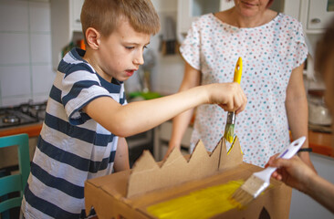 Canvas Print - Brothers painting a cardboard dinosaur costume