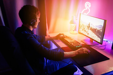 gamer plays online video games in the first person on his personal computer, sitting in a room with neon lights. Online cyber sport championship.