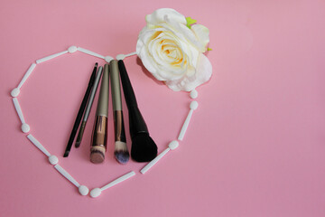 Canvas Print - a set of makeup brushes in a heart of white shadow applicators and a rose on a pink background