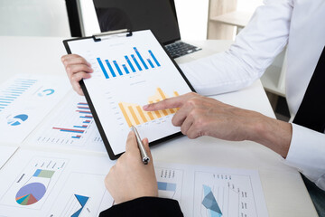 Two business people are discussing and analyze marketing strategy from the sell performance graph in the office room.