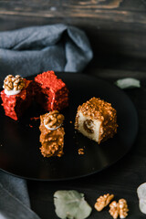 two red and chocolate cupcakes in a split on a black plate