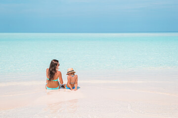 Beautiful mother and daughter at Caribbean beach enjoying summer vacation.