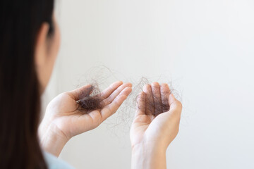 woman slicking hair falling out in two hand after facing hair loss problem by sad strain cancer patients after receiving chemotherapy. health and medical concept.