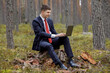 © alas_spb - freelancing in nature. a man sits on a stump and works behind a laptop in the woods.