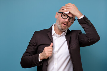 Sweating mature italian businessman in suit and glasses wiping sweat from head with napkin.