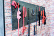 A set of varied leather lashes for sexual pleasures hang on a wooden hanger on a brick wall. Sex equipment in red and black for role-playing games. BDSM room.