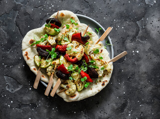 Vegetarian vegetables skewers and naan bread on a dark background, top view. Delicious tapas