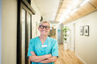 © Maskot - Portrait of mature female healthcare worker with arms crossed standing in hospital corridor