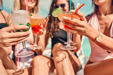 Women Clinking Glasses With Cocktails At Poolside