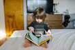 © Jessica Peterson/Tetra Images - Girl (2-3) reading book on bed