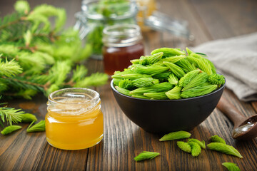 Wall Mural - Jar of honey or syrup, spruce tips in a black bowl, twigs of fir tree on wooden table.