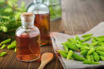 Wall Mural - Bottles of potion, syrup or honey from fir buds and needles, twigs of fir tree on wooden table.