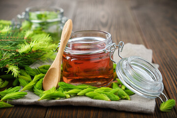 Wall Mural - Jar of  jam, syrup or honey from fir buds and needles, twigs of fir tree on wooden table. Making spruce tips jam at home.