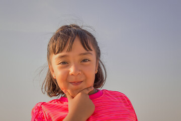 portrait of a preschool girl in a pink blouse with a blue sky background