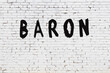 Word baron painted on white brick wall