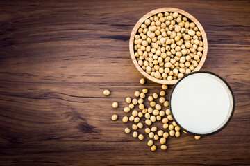 Sticker - Closeup soy beans in wooden bowl and glass of soy milk isolated on old wooden table background. Top view. Vintage style.