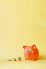 Piles of coins and piggy bank on a yellow background. Concept - saving money, accumulating finance, budget for a rainy day.