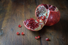 Opened Pomegranate Fruit With Red Juicy Seeds On Dark Rustic Wood, Copy Space