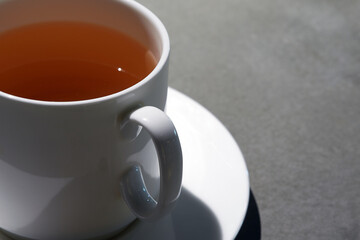 White ceramic cup with green tea on a dark table.