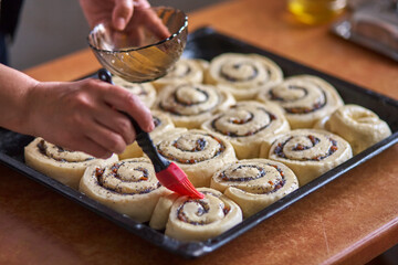 Wall Mural - A silicone pastry brush covers fresh buns. Making home biscuit rolls