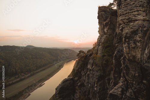 Fotografía Adventurer lying in hammock on top of mountain, between two trees with the view of a foggy mountain lake in sunrise light