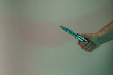 Poster - Hand holding old butterfly knife in the color light. Beautiful old minimal in neon light. Minimalism retro style concept. Background pattern for design.