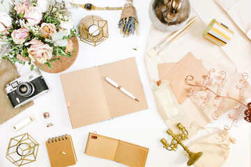 An elegant workspace of creative man in vintage style with notebook, film camera, envelope, candlestick, vase, flowers. Flat lay, top view