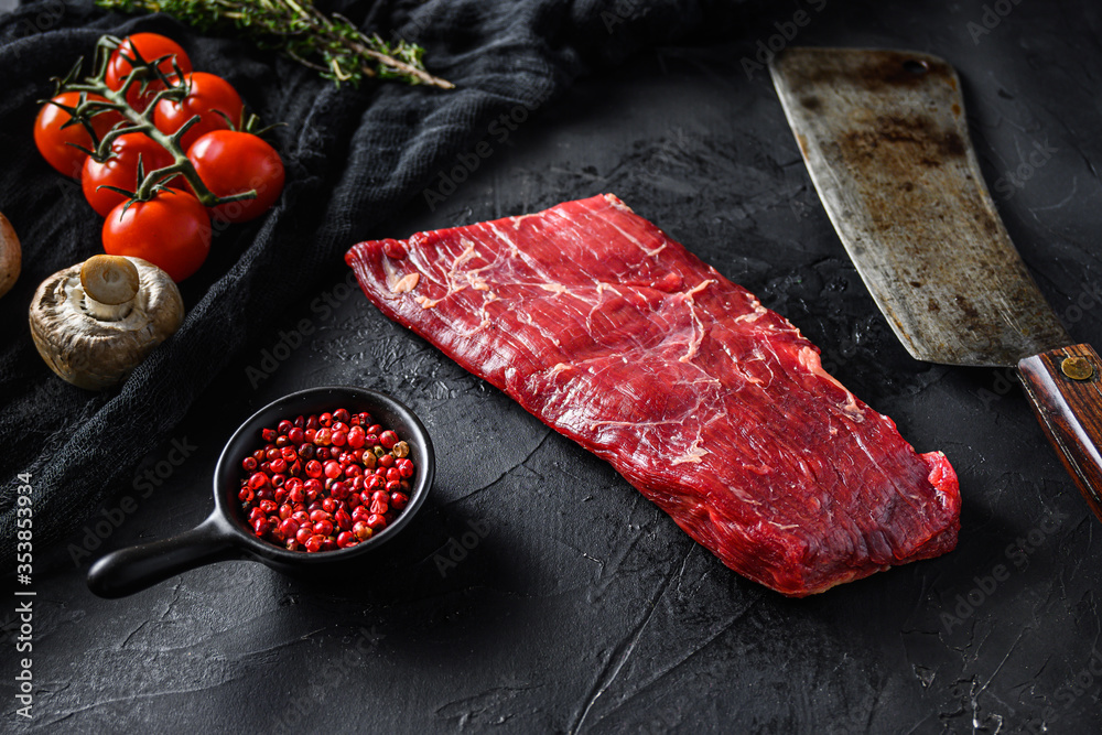 Raw, flap or flank, also known Bavette steak near butcher knife with pink pepper and rosemary. Black stone background. Side view vertical - obrazy, fototapety, plakaty 