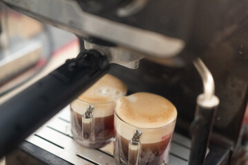 Two cups of espresso poured from a professional espresso machine