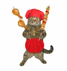 The beige cat in red cook uniform with a gold fish-bone pendant is holding two steel skewers with grill meat. White background. Isolated.