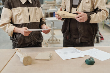 Canvas Print - Mid section of two furniture factory workers in uniform standing by workbench