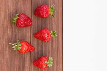 Wall Mural - red ripe fresh strawberries on a wooden background with white copisspace