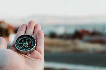 hands holding a compass ,a view of a city 