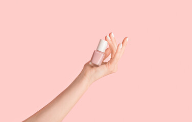 Close up of girl hands holding bottle of nail enamel on pink background, panorama