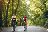 Fototapeta  - People with a bikes. Couple in a forest. Morning bike ride.