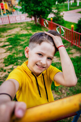 happy boy in a yellow t-shirt plays on the playground