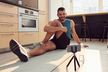 Wall Mural - Athletic gentleman working out an using cellphone at home