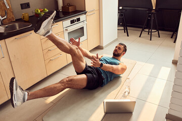 Wall Mural - Athletic young man working out in kitchen at home